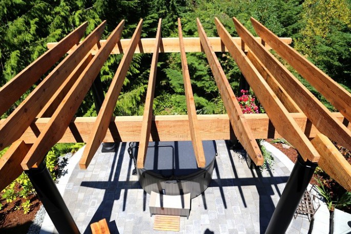 Rough sawn Cerdar pergola with Tuscan columns over a hot tub and patio. The timbers were sealed with a clear stain to allow them to silver over time to match the grey and black color scheme of the project.