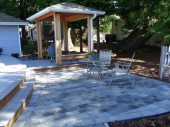 From the radius patios to the more formal but flowing deck, the use of a variety of materials and spaces allows for the smooth transition from landscape to home. The central pavilion with its built in benches can serve as a place to sit and converse
